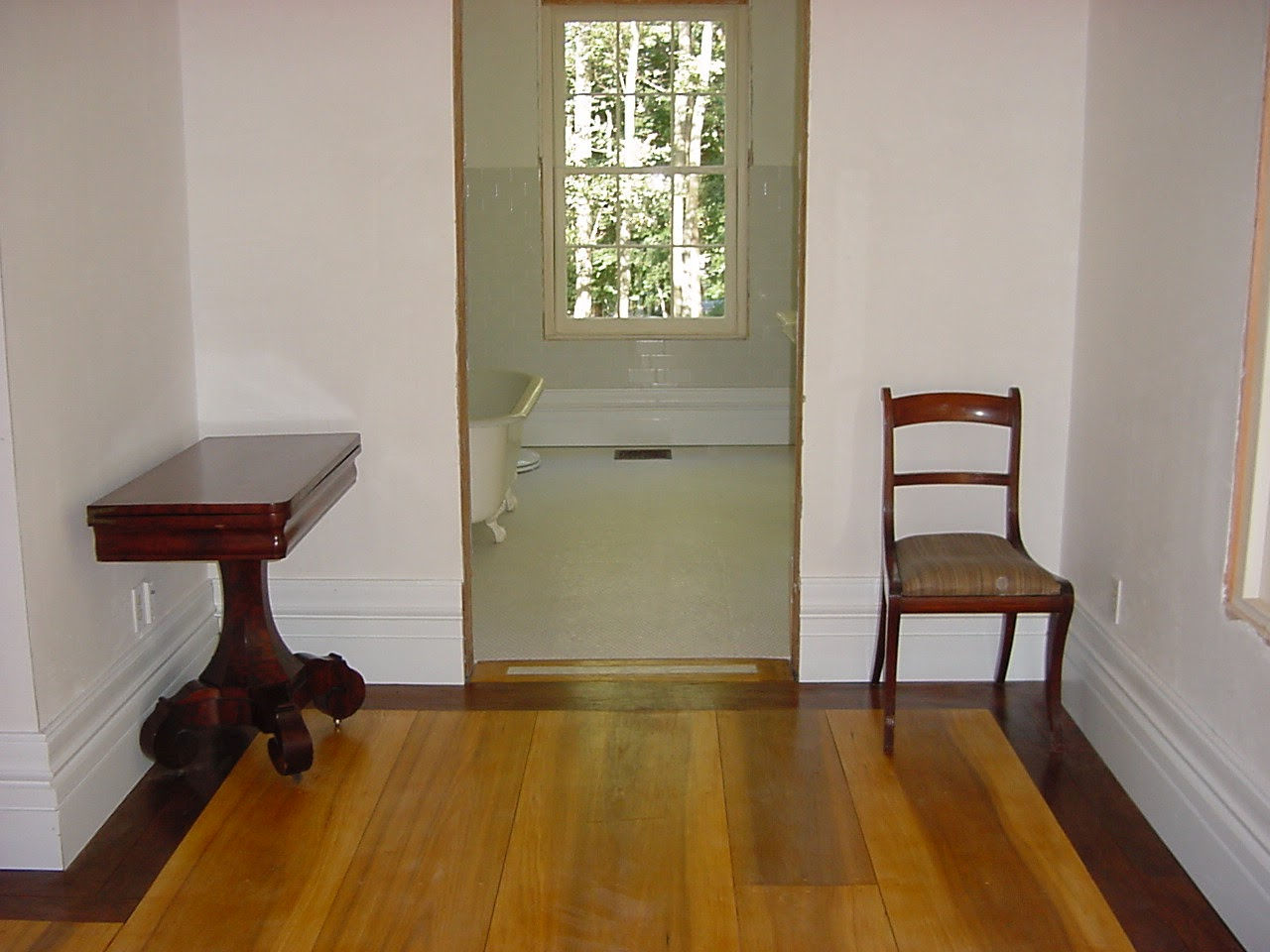 Second-floor hall looking into bathroom with clawfoot tub and hand-made window